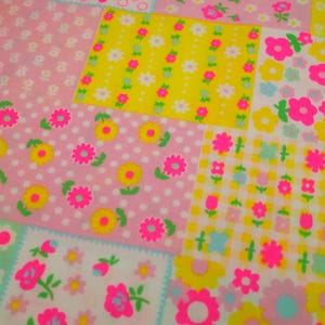 May include: A patchwork fabric featuring various floral patterns in pink, yellow, and white. The design includes polka dots, gingham, and floral arrangements with bright pink and yellow flowers, creating a cheerful and colorful aesthetic.
