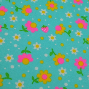 May include: Close-up of a turquoise fabric with a repeating pattern of flowers and a strawberry. The flowers are pink and yellow with green stems and leaves. White dots and yellow circles are scattered across the fabric.