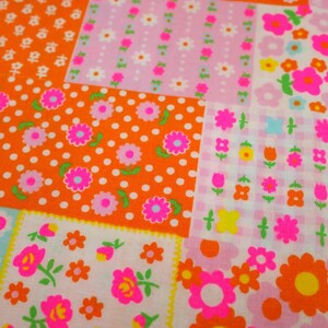 May include: A patchwork fabric with a vibrant floral pattern. The design features squares of orange, pink, and white, each adorned with different flower motifs and polka dots. The flowers are in shades of pink, orange, and yellow.