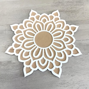 May include: White paper mandala with a brown centre, cut out in a delicate floral pattern.