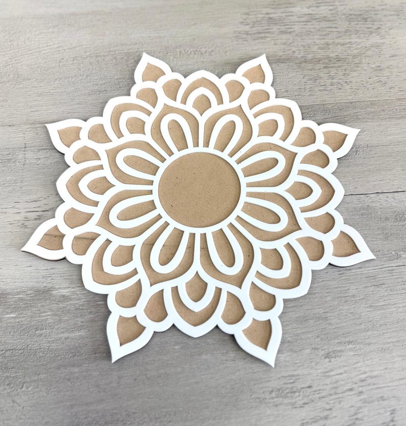 May include: White paper mandala with a brown centre, cut out in a delicate floral pattern.