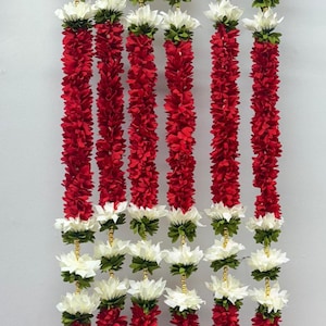Op de afbeelding: Verticale afbeelding van verschillende strengen rode bloemenslingers, afgewisseld met witte en groene bloemclusters. De slingers hangen tegen een lichtgrijze achtergrond, wat een levendige en feestelijke weergave cre&euml;ert. Elke slinger is ongeveer 122 cm lang.