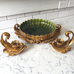 May include: A decorative set featuring a green, scalloped bowl with gold-colored handles and base, flanked by two gold-colored candle holders. The bowl is approximately 12 inches in diameter, and the candle holders are about 6 inches wide.