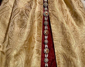 May include: A gold and red brocade dress with a long pearl and gemstone necklace.