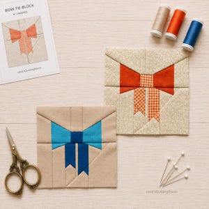Puede incluir: Dos bloques de tela cuadrados para acolchar con un patrón de pajarita, uno en naranja y otro en azul. Incluye una hoja de instrucciones de papel con la etiqueta BOW TIE BLOCK 6" FINISHED, tres carretes de hilo beige, naranja y azul, y tijeras.