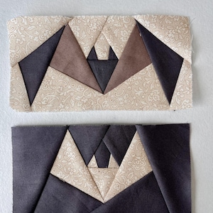 May include: Two rectangular fabric pieces with geometric designs. Each piece features a central pattern of triangles in brown and navy blue, set against a beige floral background. The top piece has brown triangles, while the bottom piece has navy blue triangles.