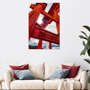 Könnte beinhalten: Ein lebendiges rotes japanisches Torii-Tor vor einem bewölkten Himmel. Das Bild fängt die architektonischen Details des Tors ein, mit Sonnenlicht, das durch die Struktur scheint. Das Kunstwerk wird über einem cremefarbenen Sofa präsentiert.