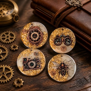 May include: Four circular resin pendants featuring gold leaf flakes and embedded metal elements. The designs include a clock face, a pair of goggles, a vintage camera, and a bee, all rendered in a metallic copper tone with intricate gear details.