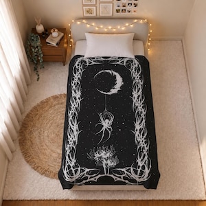 Puede incluir: Una manta de color negro y blanco con un gráfico central de una araña colgando de una luna creciente sobre un grupo de flores. El diseño está enmarcado por intrincados patrones de espinas y enredaderas sobre un fondo oscuro, cubriendo una cama.