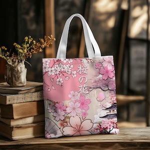 Puede incluir: Un bolso tote con asas blancas y un diseño floral rosa. El diseño presenta flores de cerezo, una pagoda japonesa y el texto japonés "桜の花" (Sakura no Hana), que significa "flores de cerezo". El fondo es un degradado de rosa y beige.