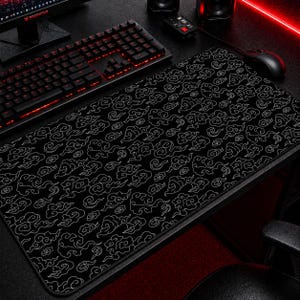 May include: Black extended mouse pad with a white cloud pattern. The pad is rectangular and covers a large portion of a desk. A black keyboard and mouse are visible on the desk.