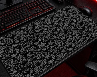 May include: Black extended mouse pad with a white cloud pattern. The pad is rectangular and covers a large portion of a desk. A black keyboard and mouse are visible on the desk.