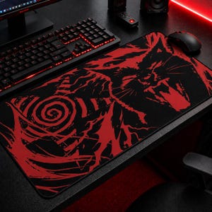 May include: Black and red gaming mouse pad with a stylized cat design. The mouse pad features a black background with a red graphic of a cat's face and abstract shapes. A black keyboard and mouse are visible.