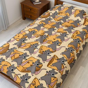 Puede incluir: Una sábana beige con un patrón repetido de ratas grises de dibujos animados y bloques de queso amarillos. Las ratas tienen colas rosas y ojos negros. Los bloques de queso tienen agujeros.