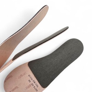 Peut inclure: Gros plan de trois semelles int&eacute;rieures de chaussures. Les semelles int&eacute;rieures sont beiges et noires, avec une surface textur&eacute;e. Les semelles int&eacute;rieures sont dispos&eacute;es &agrave; diff&eacute;rents angles sur un fond blanc. Les semelles int&eacute;rieures sont &eacute;tiquet&eacute;es avec du texte.