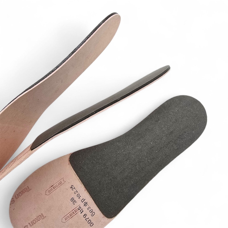 Peut inclure: Gros plan de trois semelles int&eacute;rieures de chaussures. Les semelles int&eacute;rieures sont beiges et noires, avec une surface textur&eacute;e. Les semelles int&eacute;rieures sont dispos&eacute;es &agrave; diff&eacute;rents angles sur un fond blanc. Les semelles int&eacute;rieures sont &eacute;tiquet&eacute;es avec du texte.