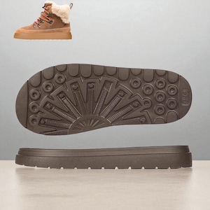 May include: A tan-colored boot with a brown sole and a cream-colored fur lining. The sole is brown with a textured pattern. The boot has brown laces and a brown heel. The boot is a winter style.