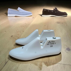 May include: A light blue suede loafer with a white sole and a brown suede boat shoe with a white sole are displayed. Two white shoe forms are in the foreground, with the text "ITAL STEP AC 1056 T 39".