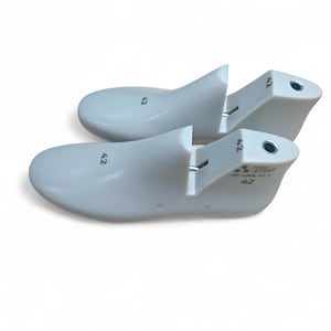 May include: Two white shoe lasts, size 42, are displayed against a white background. The lasts are made of a smooth, solid material and have a curved shape to fit the foot. The number 42 is printed on each last.