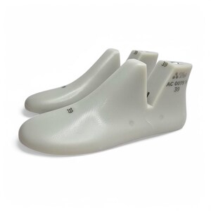 May include: Two white shoe lasts, size 39, are displayed against a white background. The lasts are made of a smooth, solid material and are designed to maintain the shape of shoes. The text "39" is printed on the lasts.