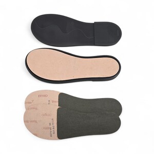 Peut inclure: Trois composants de chaussures sont pr&eacute;sent&eacute;s : une semelle en caoutchouc noire, une semelle int&eacute;rieure beige et deux semelles int&eacute;rieures gris fonc&eacute;. La semelle noire est con&ccedil;ue pour le bas d'une chaussure. La semelle int&eacute;rieure beige est une insertion en forme de pied.