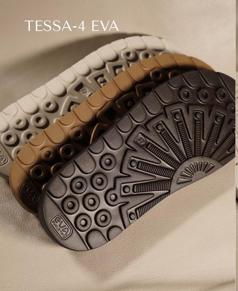 May include: Close-up of three EVA shoe soles in white, tan, and dark gray. The soles have textured patterns and the text "TESSA-4 EVA" is at the top. The soles are stacked at an angle, showcasing their design and material.