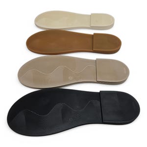May include: Four different colored shoe soles are displayed. The colors are beige, brown, tan, and black. The soles have a textured surface and a rectangular heel. The soles are for sandals or other types of footwear.