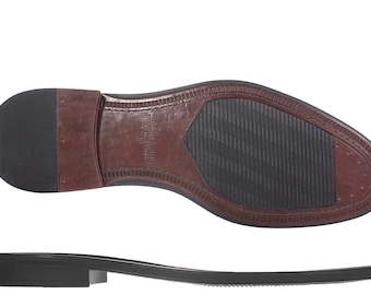 May include: Bottom view of a brown leather dress shoe sole with a black rubber heel and a black rubber section in the middle. The sole has a textured design for grip and the brand name is visible.