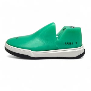 May include: A green shoe-shaped shoe stretcher with a white sole and the text "LUSI T" on the side.