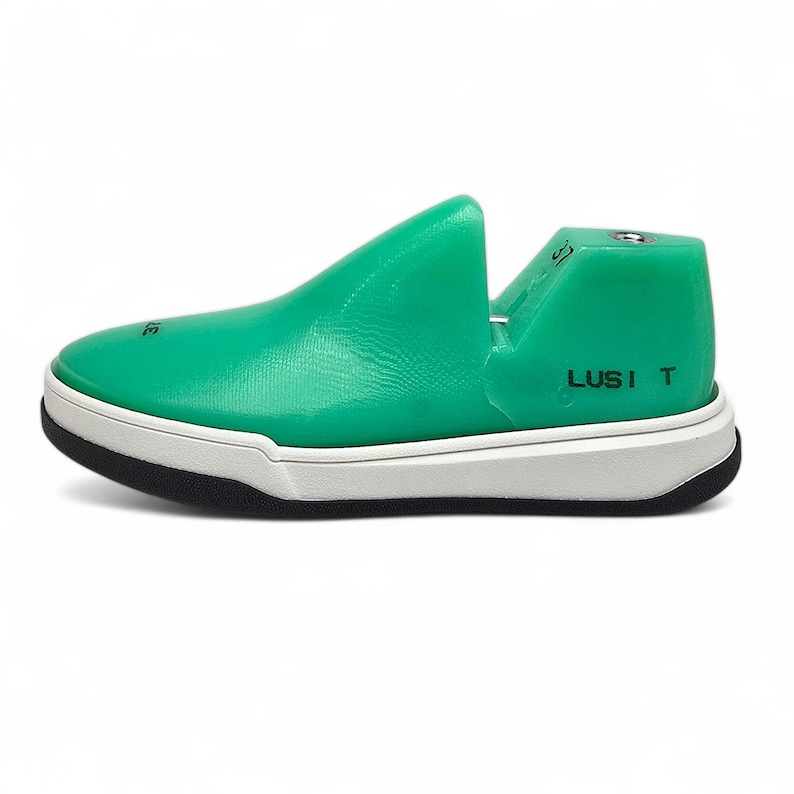 May include: A green shoe-shaped shoe stretcher with a white sole and the text "LUSI T" on the side.