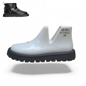 Puede incluir: Botín de cuero negro con detalle de cadena plateada y suela gruesa. También se muestra una horma de zapato blanca con el texto "ITAL STEP AC YUGA Y 39". El botín tiene punta redonda y tacón bajo.