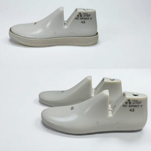 Op de afbeelding: Twee paar off-white schoenmallen met een afgeronde neus en hielondersteuning. De tekst "ITAL STEP AC SPIRIT T 43" staat op de hiel. Maat 43, ongeveer 27 cm.