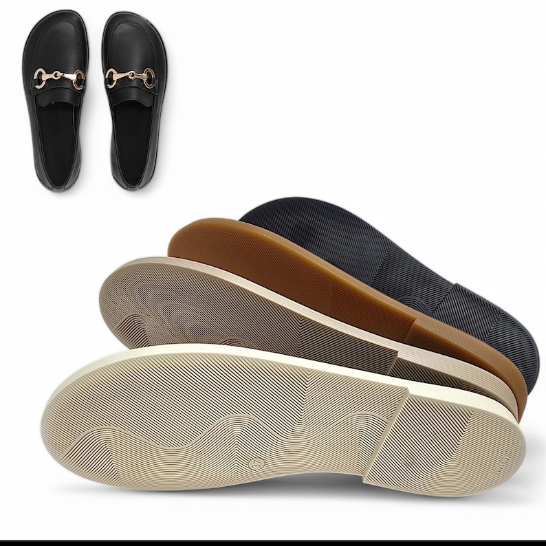 May include: Black loafers with gold-colored horsebit detail, displayed with the soles of several pairs of shoes in various colors: beige, brown, and black. The soles have a textured, ridged pattern.