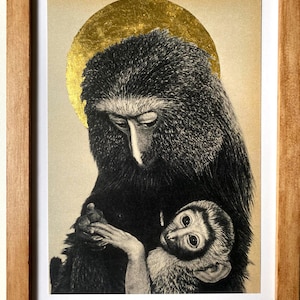 May include: A framed art print featuring a detailed black and white illustration of a large monkey holding a small infant monkey. Behind the larger monkey's head is a circular gold leaf halo. The artwork is enclosed in a simple light wood frame.