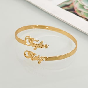 May include: Gold-toned bangle bracelet with the names "Taylor" and "Reign" engraved on it.