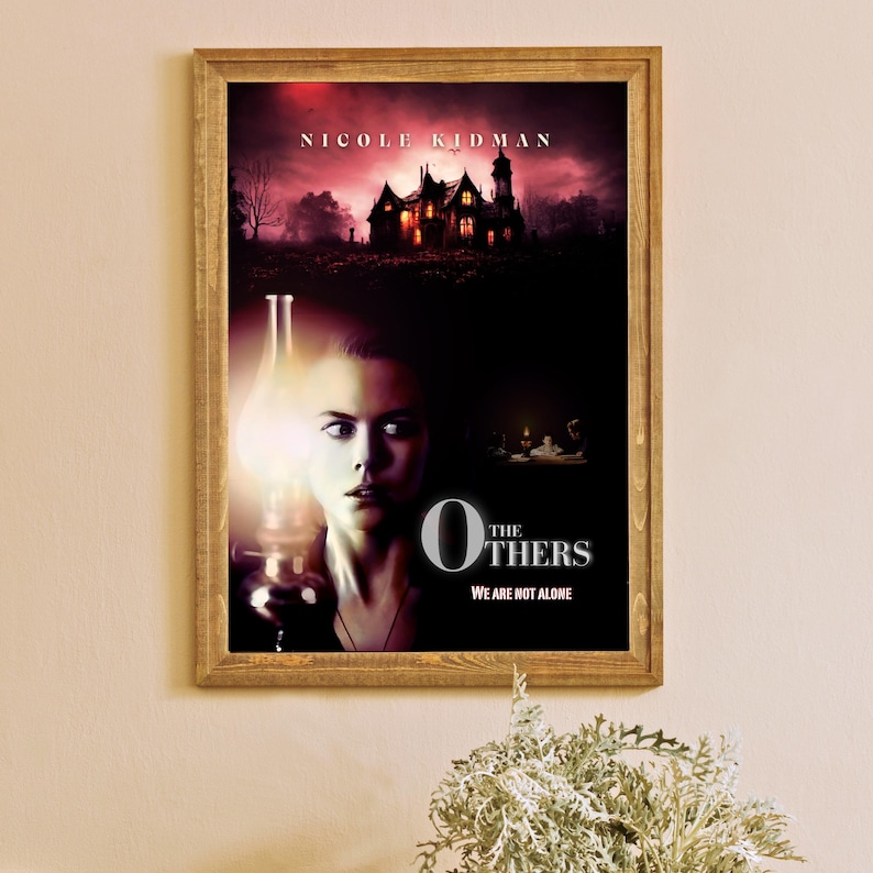 May include: Movie poster for the film "The Others" starring Nicole Kidman. The poster features a dark, gothic house and a woman holding a lantern. The text "The Others" is in large, white letters with the tagline "We are not alone" below.