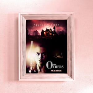 May include: A movie poster for the film "The Others" starring Nicole Kidman. The poster features a woman with a worried expression, a large house in the background, and the title "The Others" in large, bold letters. The tagline "We are not alone" is printed below the title.