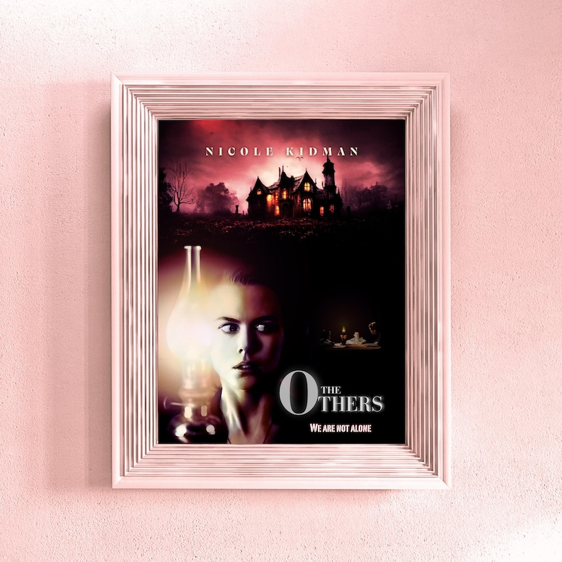 May include: A movie poster for the film "The Others" starring Nicole Kidman. The poster features a woman with a worried expression, a large house in the background, and the title "The Others" in large, bold letters. The tagline "We are not alone" is printed below the title.