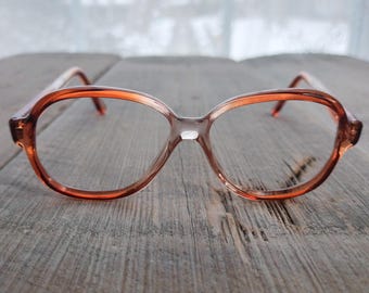 May include: A pair of brown plastic framed spectacles with oval lenses.