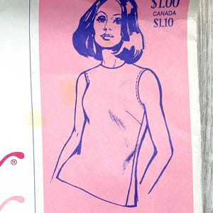 May include: A vintage sewing pattern envelope featuring a purple line drawing of a person wearing a sleeveless top. The background is pink with text that reads U.S.A. $1.00, CANADA $1.10, and STRETCH & SEW FABRIC CENTER at the bottom of the paper.
