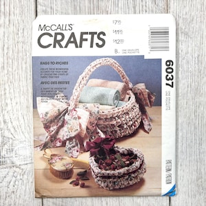 May include: McCall's Crafts pattern envelope featuring a crocheted basket with rolled towels, a heart-shaped container, and a brush. The text reads "Rags to Riches" and "Create these wonderful accents for your home by crocheting strips of fabric together."