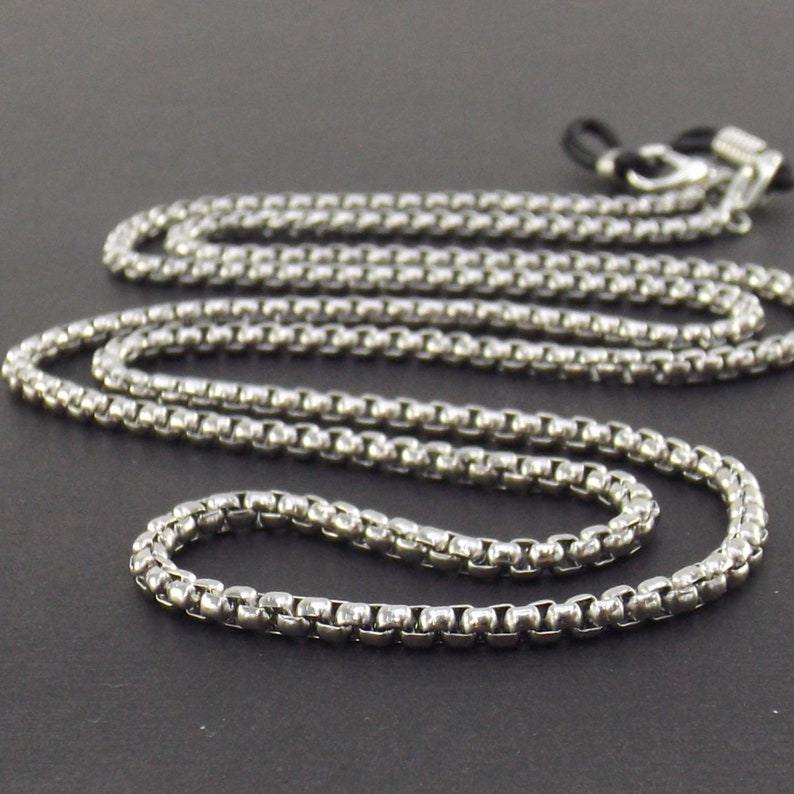 May include: Silver chain with black rubber ends for holding glasses.