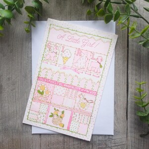 以下が含まれることがあります： ピンクとグリーンのベビーシャワーカードに「A Little Girl!」の文字と、ベビーバニー、ベビーラム、ベビーチキン、ベビーアイスクリームコーンが描かれたパッチワークデザインが施されています。
