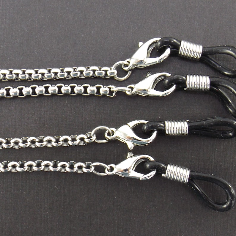 May include: Three silver eyeglass chains with black rubber ends. Each chain has a different style of link.