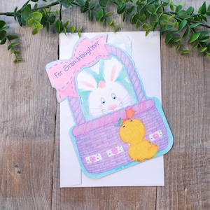 Tarjeta de felicitación de Pascua para nieta, hecha en EE. UU., con un conejito, una cesta y un pollito.