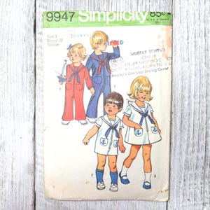 Op de afbeelding: Vintage Simplicity naaipatroon 9947 voor matrozenoutfits voor peuters. Het patroon toont illustraties van kinderen in rode, blauwe en witte matrozenkleding. Het patroon bevat de tekst "Size 3 Breast 22 Toddler" en "Murray Sewing Center".