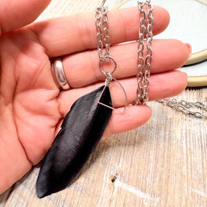 silver charm necklace with a feather charm, black