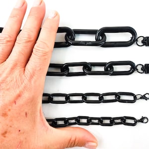 Może przedstawiać: Cztery czarne plastikowe łańcuchy o różnych długościach. Łańcuchy są połączone ze sobą w ciągłą pętlę.