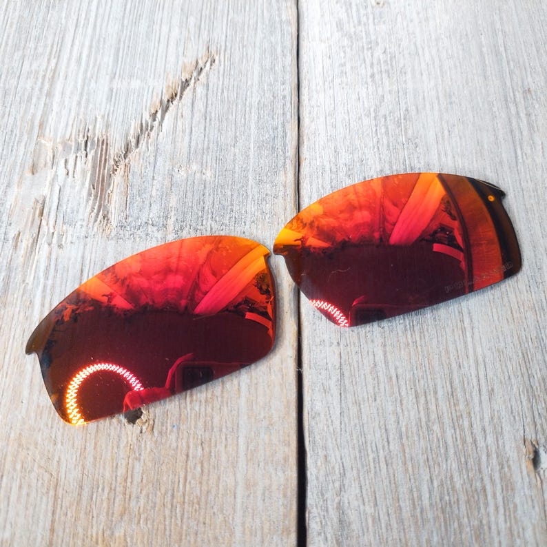 Puede incluir: Un par de lentes de repuesto para gafas de sol, de color rojo espejo. Las lentes son curvadas y tienen un acabado reflectante.