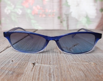 May include: Blue plastic sunglasses with a gradient lens. The sunglasses have a thin frame and a rectangular shape.